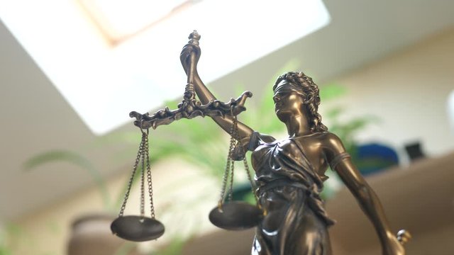 Statue of Themis or Lady Justice on Bookshelf Background. Law Firm or Business Concept. Corporate or business, enterprise or company law