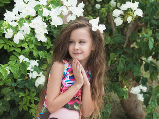 Portrait of lovely little girl on blooming tree background.