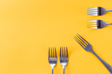 Holiday, table setting, cutlery . Minimal modern concept Luxury festive party background. Silver forks isolated on yellow background. vibrant summer party banner.Minimalism concept. Pop art style