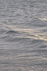 Waving surface of stormy sea water on a sunset with reflection of the sunlight.