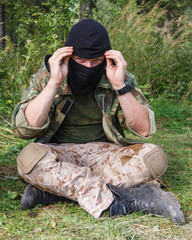 military man in camouflage and a black mask is sitting in the forest. terrorism and separatism the...