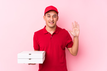 Young pizza delivery latin man isolated smiling cheerful showing number five with fingers.