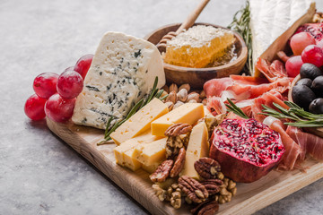 Traditional italian antipasto plate. Assorted cheeses on wooden cutting board. Brie cheese, cheddar...