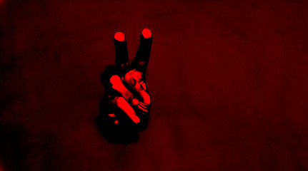 Male hand with the two finger. Body language concept with hole in red paper wall. Hand Peace Sign....