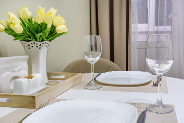 Closeup of empty wine glasses on banquet table with cutlery and Bouquet of yellow tulip flowers