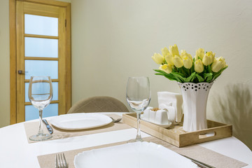 Closeup of empty wine glasses on banquet table with cutlery and Bouquet of yellow tulip flowers
