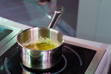 The metal ladle on the stove. The cooking of the sauce. Cheese sauce for spaghetti. Recipes of national dishes. Equipment of cafes and restaurants. Varied menu.