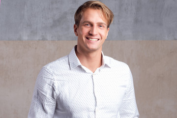 young positive guy in a business white shirt without a tie, looking at the camera,