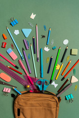 School stationery on green background. The concept banner with student supplies for back to school with pencils case, notes, paper clips, pins, sharpener, scissors, pencils and other tools. Mockup.