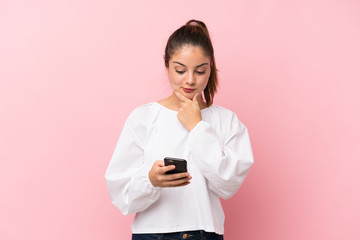 Young brunette girl over isolated pink background thinking and sending a message