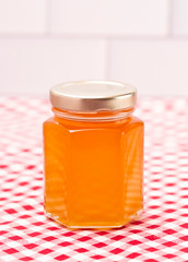 Jar of Fresh Raw Organic Honey on a Red and White Table Cloth