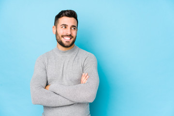 Young caucasian man against a blue background isolated smiling confident with crossed arms.