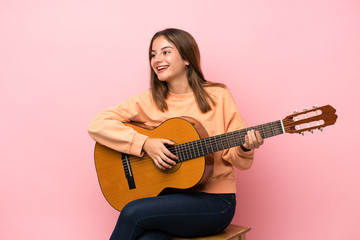 Fototapeta premium Young brunette girl with guitar over isolated pink background
