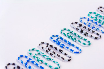 Stationery striped paper clips laid out in a row. Top view, flat lay. Back to school, college, education concept. Collection of colorful paper clips. Abstract background.