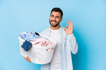 Young handsome man doing laundry isolated cheerful and confident showing ok gesture.