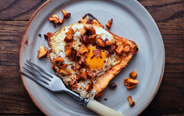 Hot homemade grilled toast with mustard sauce, fried eggs and wild mushrooms in a plate