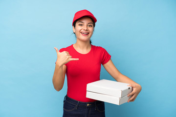 Young woman holding a pizza over isolated pink wall making phone gesture