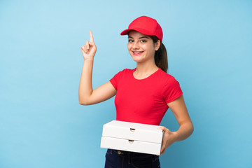 Young woman holding a pizza over isolated pink wall pointing with the index finger a great idea