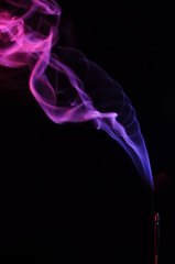 lilac smoke incense sticks on a black background. abstract figures of blue smoke on a black background