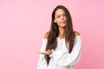 Young Brazilian girl over isolated pink background presenting an idea while looking smiling towards