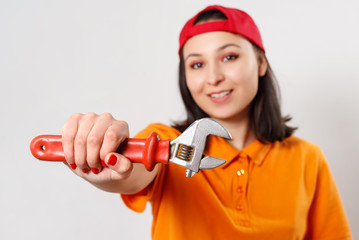 portrait of a young woman with a wrench in her hand. on white background