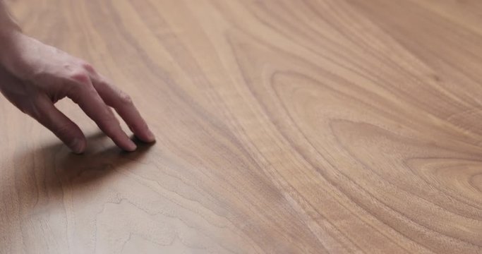 Slow motion man hand touches black walnut dining table surface