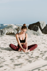Fototapeta na wymiar Young Woman Practicing Yoga On The Beach By The Ocean, Yoga Poses Set Against Beautiful Background