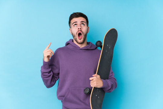 Young Caucasian Skater Man Isolated Pointing Upside With Opened Mouth.