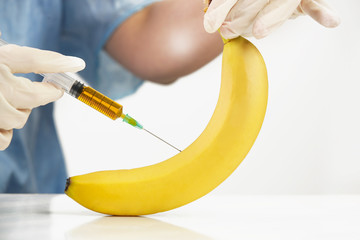 Closeup of needle injected into banana fruit, Genetically engineered food concept - obrazy, fototapety, plakaty