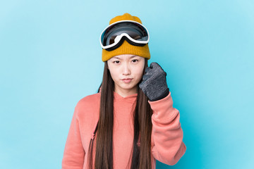 Young chinese woman wearing ski clothes isolated showing fist to camera, aggressive facial expression.