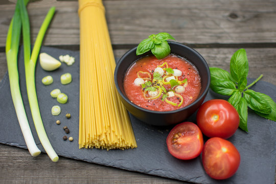 fruity tomato sauce in a bowl decorated with spring onions and basil. Served with raw spaghetti.