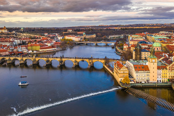 Obraz premium Prague, Czech Republic - Aerial panoramic drone view of the world famous Charles Bridge (Karluv most) and St. Francis Of Assisi Church with a beautiful winter sunset and sky