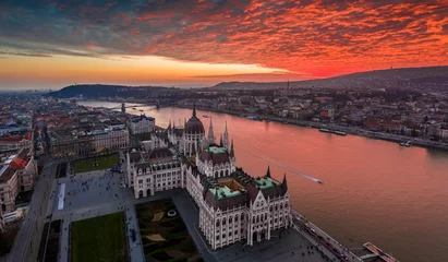 Photo sur Plexiglas Széchenyi lánchíd Budapest, Hungary - Aerial panoramic drone view of the Hungarian Parliament building on a winter afternoon with an amazing dramatic colorful gold and red sunset sky