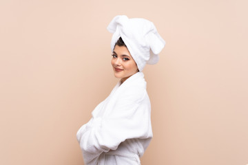 Teenager girl in a bathrobe over isolated background laughing