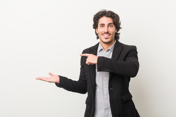 Young business man against a white background excited holding a copy space on palm.