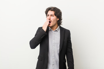 Young business man against a white background yawning showing a tired gesture covering mouth with hand.