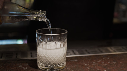 Pouring soda in glass with ice