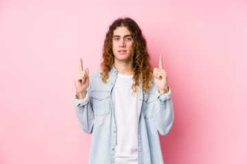 Long hair man posing isolated indicates with both fore fingers up showing a blank space.