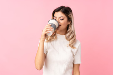 Teenager girl over isolated pink background holding and drinking a coffee to take away