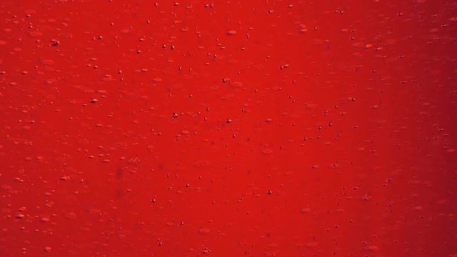 Tiny air bubbles raising in red abstract liquid