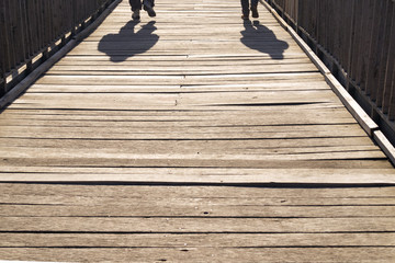  the shadow of two people walking across the bridge