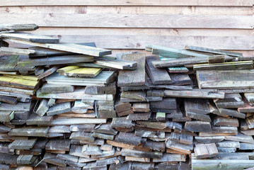Many old weathered boards stacked against wooden wall