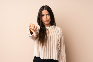 Young woman over isolated background showing thumb down with negative expression