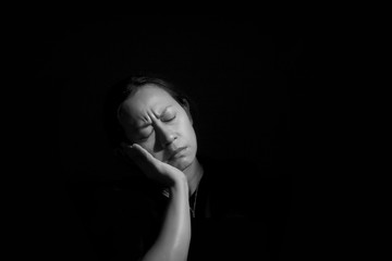 ASIAN ART PORTRAIT Gray monochrome one adult middle aged Thai woman frown face as housewife or mom repine angry serious waiting alone worry sad and unhappy with isolated black background COPY SPACE