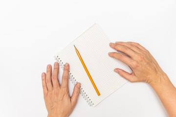 Woman hands holding a notebook and a yellow pencil ready to write, close up top view