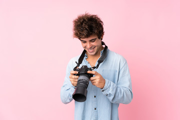 Young caucasian man over isolated pink background with a professional camera