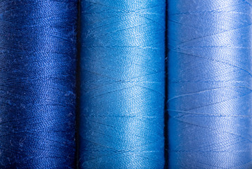 three spools of thread shades of blue. background.  close up.