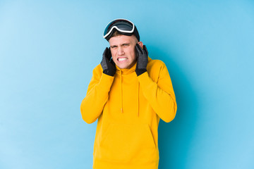 Young skier man covering ears with hands.