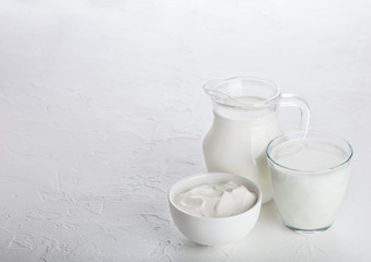 Jar and glass of milk and bowl of sour cream on white stone kitchen table background.Space for text