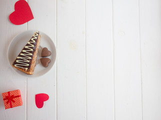 Slice of cake on a saucer and hearts on a white background.